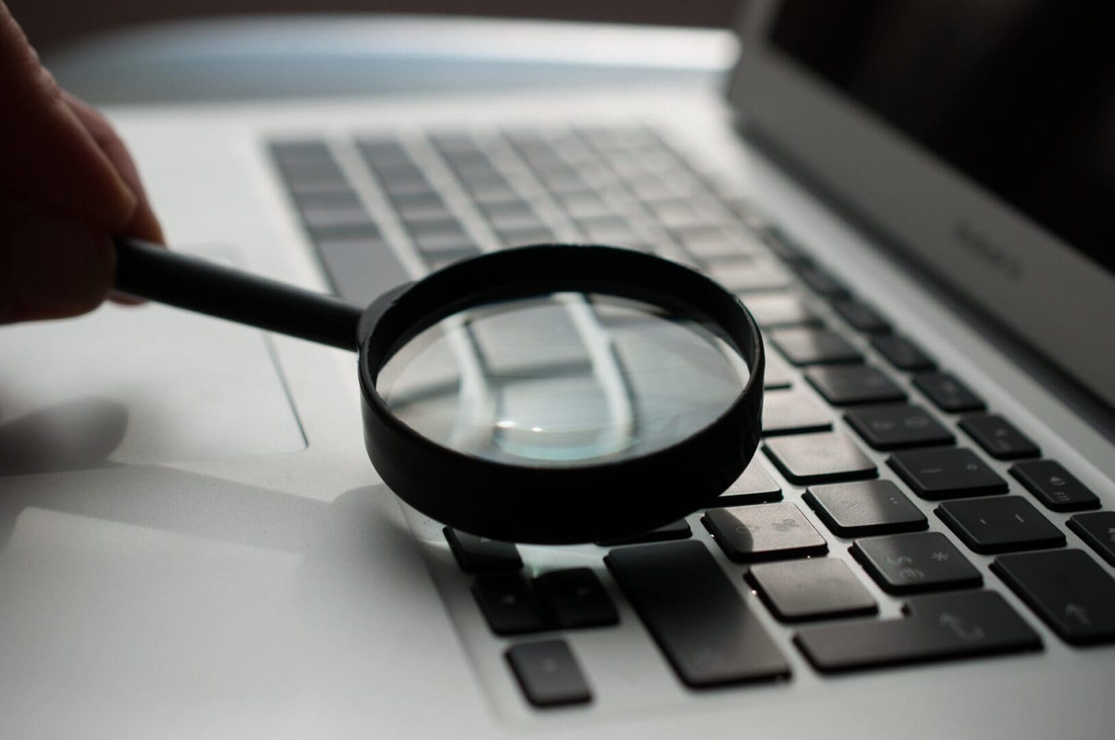 A magnifying glass sitting on top of a laptop keyboard.